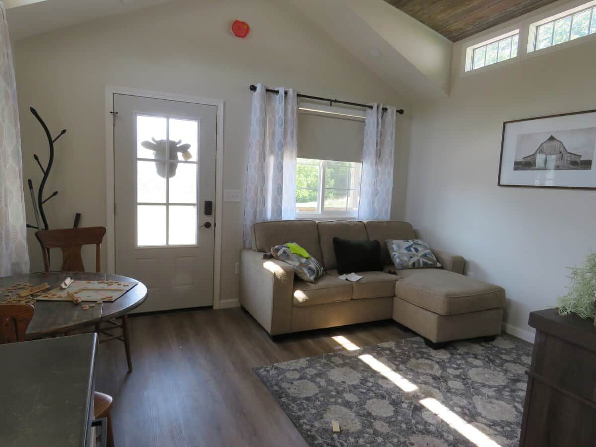 A living room with a sofa, a dining table, and a window with curtains.