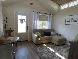 Una sala de estar con sofá, mesa de comedor y ventana con cortinas.