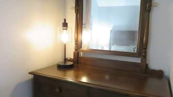 A wooden dresser with a mirror and a light fixture.