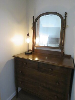 A wooden dresser with a mirror and a light fixture.