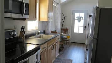 A kitchen with wooden cabinets, a microwave, a refrigerator, and a sink.