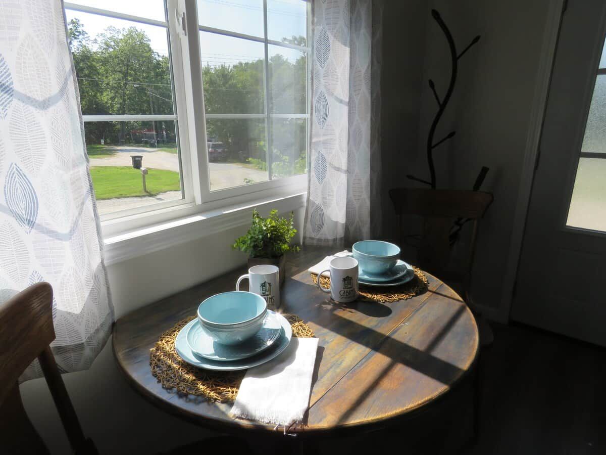 Una mesa de comedor con platos azules y tazas a juego, sobre una mesa de madera con un camino de mesa de encaje.