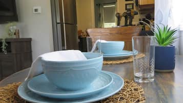 A dining table with blue plates and bowls, a woven placemat, and a potted plant.