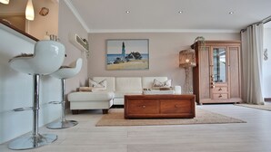 Un salón moderno con un sofá blanco, una mesa de centro de madera y un cuadro de un faro.
