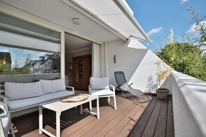 Un balcon avec un canapé blanc, une petite table et une chaise.