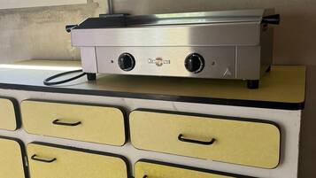 A kitchen with a stainless steel appliance on top of a yellow cabinet with handles.