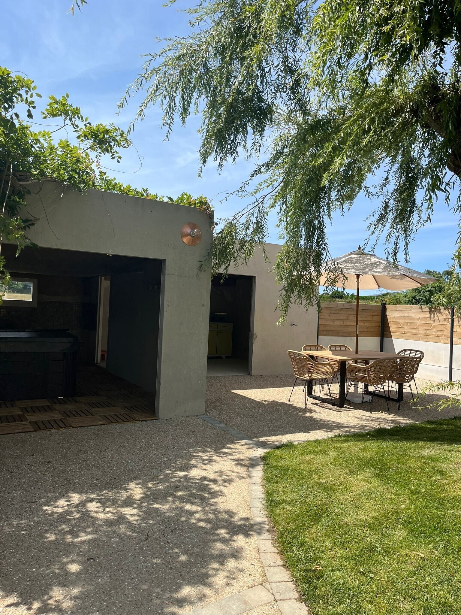 Un espace extérieur aménagé avec une table et des chaises, un barbecue et un coin salon abrité.