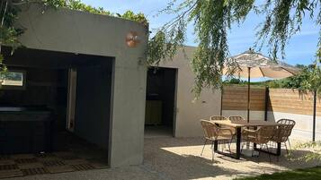 Un espace extérieur aménagé avec une table et des chaises, un barbecue et un coin salon abrité.