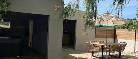 A patio area with a table and chairs, a grill, and a covered seating area.