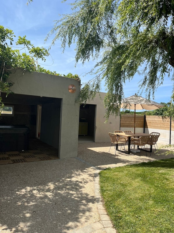 A patio area with a table and chairs, a grill, and a covered seating area.