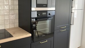 Une cuisine équipée d’un four à micro-ondes, d’un four, d’un réfrigérateur et d’un plan de travail en bois.