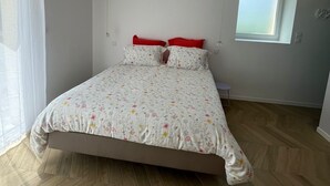 Une chambre à coucher avec un lit, une fenêtre et un luminaire au plafond.