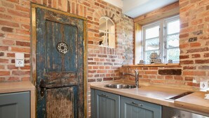 Une cuisine avec un mur en briques au style rustique, une porte en bois, une fenêtre et un évier en acier inoxydable.