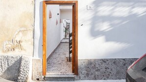 Un couloir étroit avec une porte en bois, une plaque portant le numéro « 34 », et un petit escalier menant à une autre porte.