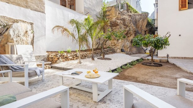 Une terrasse dotée de meubles blancs, d’une table blanche et d’un décor rocheux en arrière-plan.