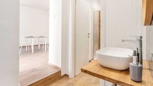 Une salle de bain moderne avec un grand lavabo blanc, un plan de toilette en bois et un miroir.