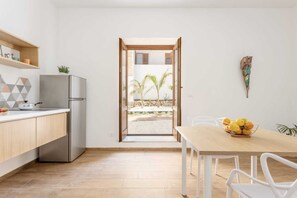 Une cuisine moderne avec un coin repas, un réfrigérateur, une table en bois et une vue sur l’extérieur.