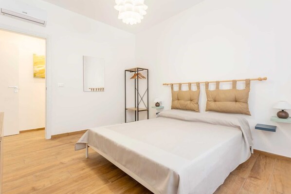 A bedroom with a bed, bedside tables, a wardrobe, and a hanging light fixture. - Apartment 'Travel Rooms-Arenella Piano Terra 1' with Mountain View, Wi-Fi and Air Conditioning (Palermo)