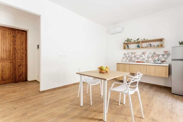 A modern kitchen with white cabinets, a wooden door, and a tiled backsplash.