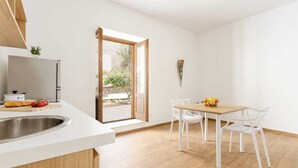 A modern kitchen with a built-in fridge, a sink, and a dining area with a table and chairs. - Apartment 'Travel Rooms-Arenella Piano Terra 1' with Mountain View, Wi-Fi and Air Conditioning (Palermo)