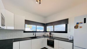 A modern kitchen with white cabinets, a black countertop, a built-in oven, and a window above the sink. - Vacation Home 'Villa Maria' with Mountain View, Wi-Fi and Air Conditioning (Playa Blanca)