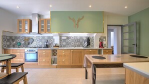 A modern kitchen with patterned backsplash, wooden cabinets, and a central island. - Le Gîte du Sourcier – Authentic and Welcoming Stay in Dordogne (Sadillac)
