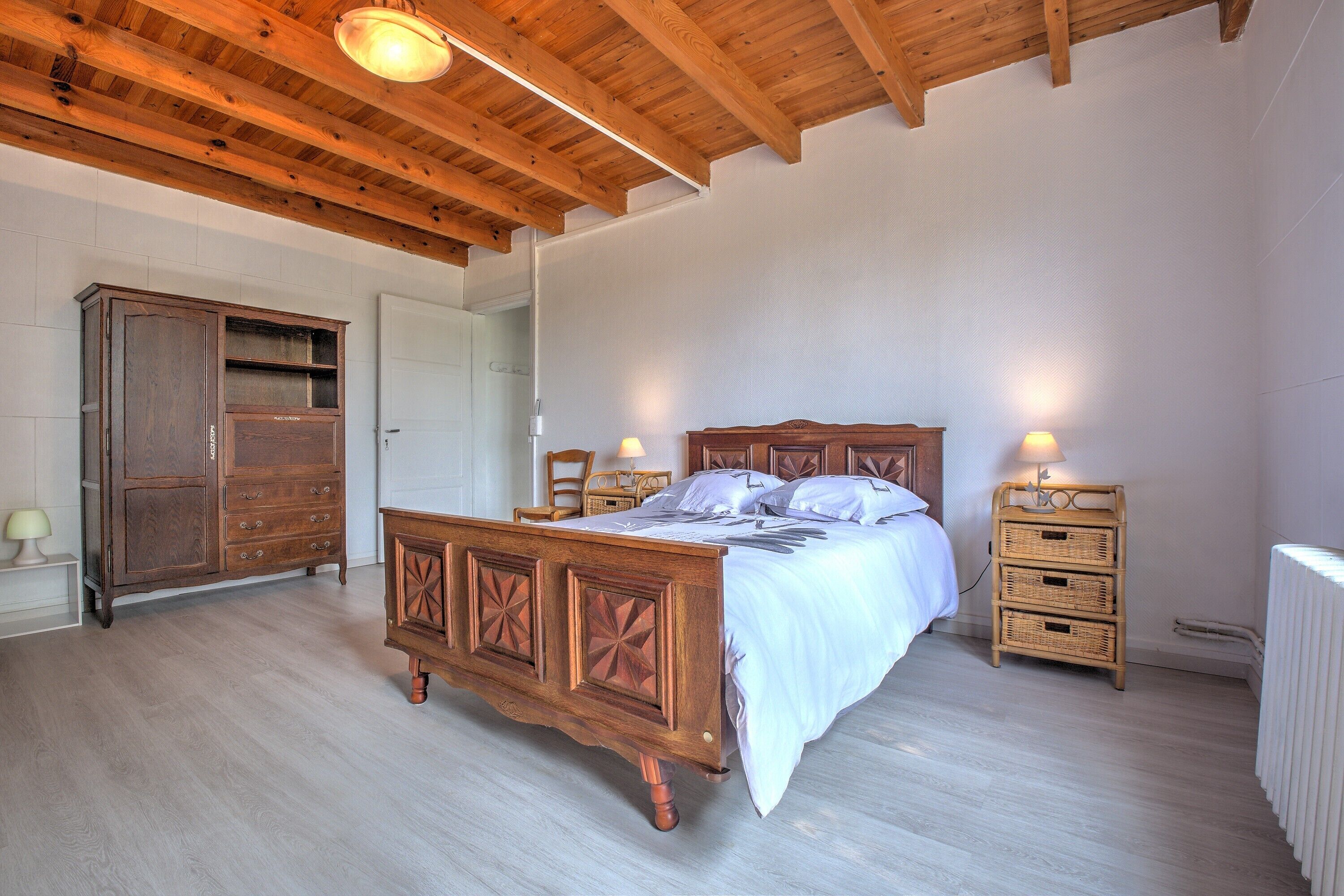 A bedroom with a wooden bed, a wardrobe, a nightstand, and a radiator.