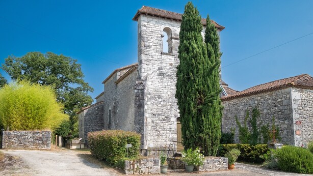 A stone building with a tower, surrounded by greenery and a gravel driveway. - Le Gîte du Sourcier – Authentic and Welcoming Stay in Dordogne (Sadillac)
