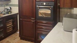 A kitchen with dark wooden cabinets, a built-in oven, a toaster, and a tiled backsplash.