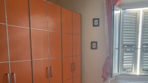 A room with a tiled floor, a window with shutters, and a radiator.