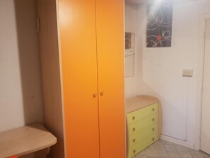 Una stanza con un armadio, una panca, un tavolino e una mensola a muro.