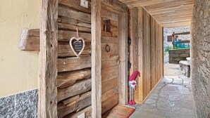 Ein Holzbodenkorridor mit einer Steinsäule, einer Tür mit Herzverzierung und einer Gartenzwergfigur.