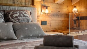 Ein gemütliches Schlafzimmer mit einem Holzkopfteil, gemusterten Kissen, einem Nachttisch und einer Wandleuchte.