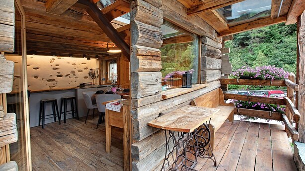 Ein rustikales Holzinterieur mit Barbereich, Barhocker und einem großen Fenster mit Blick auf Grünflächen.