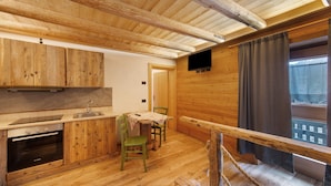 Un interior de madera con cocina, comedor y ventana con cortinas.
