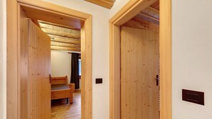 A wooden interior with a bench, wooden doors, and a light switch on the wall. - Apartment 'Ciariè' with Mountain View (Auronzo di Cadore)