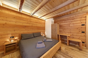 Une pièce de cabane en bois comprenant un lit, des tables de chevet, un banc et une armoire.