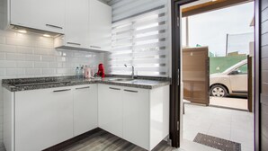 A modern kitchen with white cabinets, a granite countertop, and a stainless steel sink.