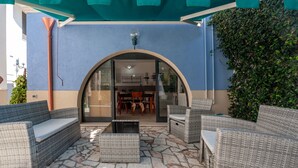 An outdoor patio area with wicker furniture, a stone floor, and a view into the building.