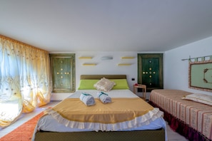 A hotel room with a large bed, two bedside tables, a green headboard, and a window with curtains.