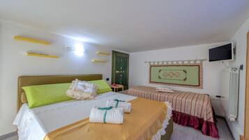 Une chambre d’hôtel avec un lit, un deuxième lit, une télévision, un radiateur et une porte.