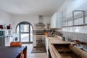 A kitchen with a washing machine, oven, sink, and a small dining area with a table and chairs.