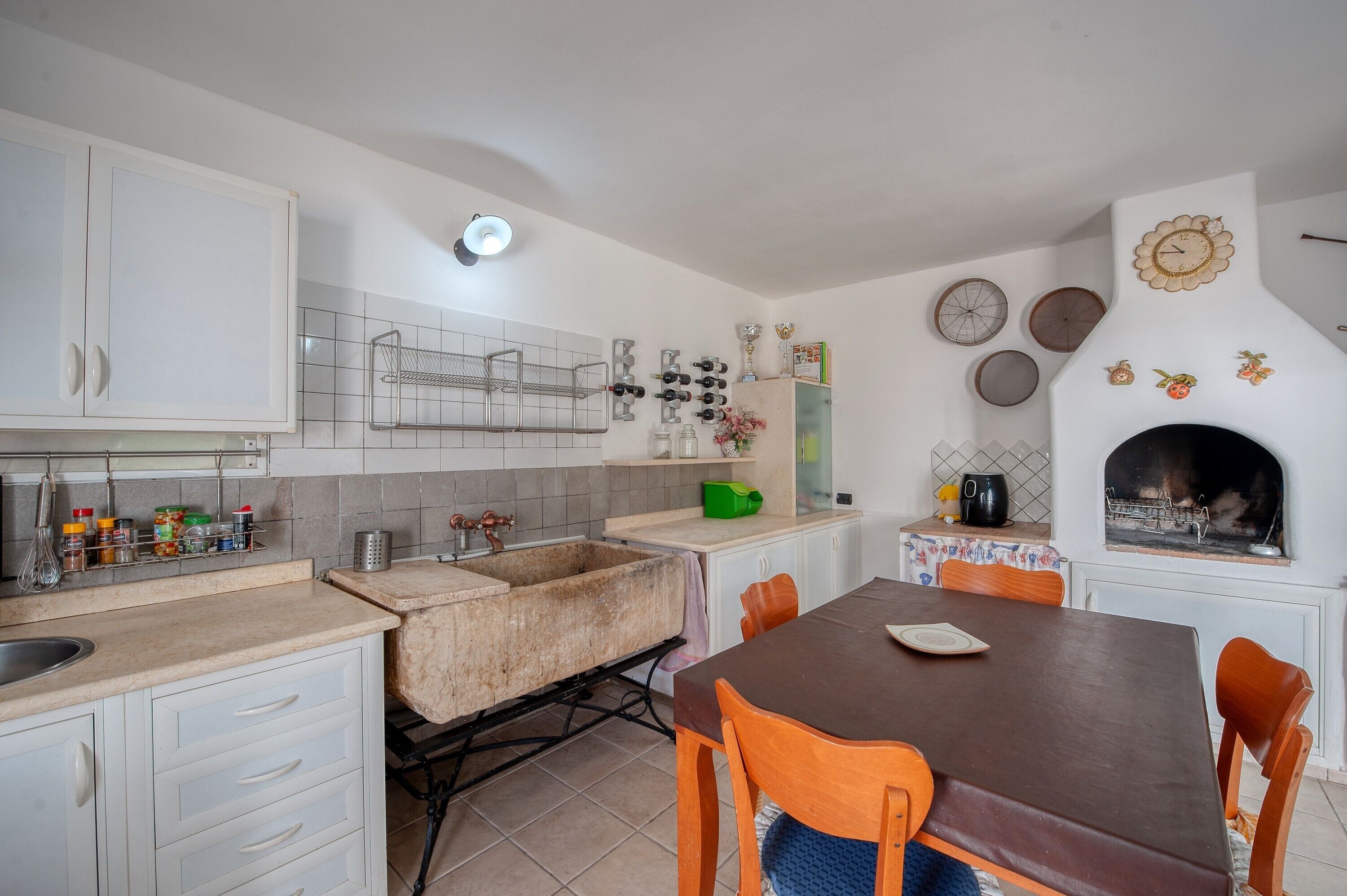 A kitchen with white cabinets, a sink, a stove, and a dining table with chairs.
