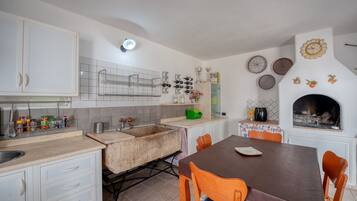 A kitchen with white cabinets, a sink, a stove, and a dining table with chairs.