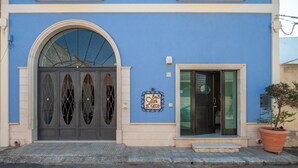 A building with a blue facade, a large arched entrance, and a sign reading 'B&B Il Gecco.'