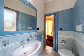 Un baño con un espejo grande, una bañera, un inodoro y una zona de ducha.