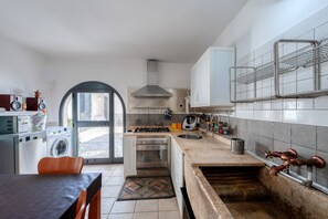 Eine Küche mit Waschmaschine, Backofen, Spüle und einer kleinen Essecke mit Tisch und Stühlen.