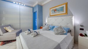 A bedroom with a bed, a chair, a nightstand, a painting, and a blue door.