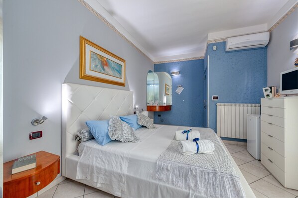 Un dormitorio con cama, mesita de noche, aire acondicionado instalado en la pared y televisión.