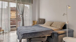 Un dormitori amb un llit, un radiador, una làmpada de peu i una vista per la finestra.